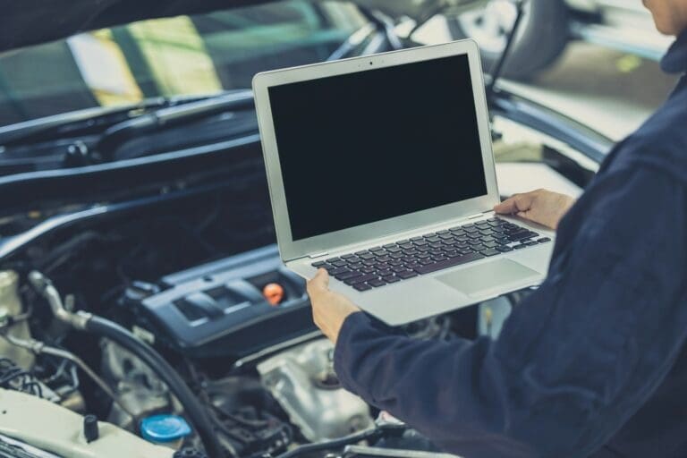 laptop computer blank screen with modern car engine performance ECU tune up in auto garage workshop
