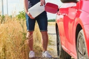 Man filling up fuel or diesel into the gas tank from canister in the field,