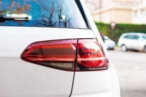 Rear red light of the car with blurred city parking in the background