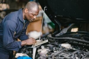 Garage professional working auto service checking engine. Mechanic man using tablet computer tuning