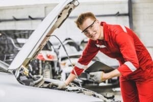Happy Mechanic young male staff worker working with car engine front hood auto service check tuning