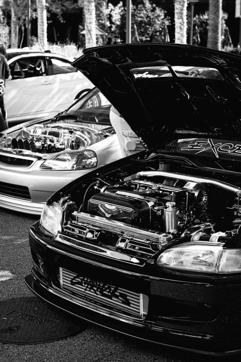 Two cars with hoods open showing engines