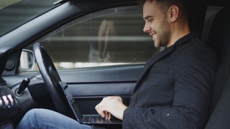 Man working on laptop inside a car