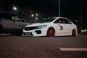 a white car with red rims parked in a parking lot